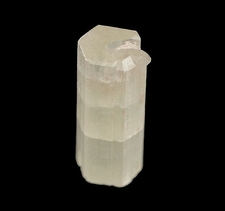 A partially transparent, elongated crystal with a faceted surface against a black background.
