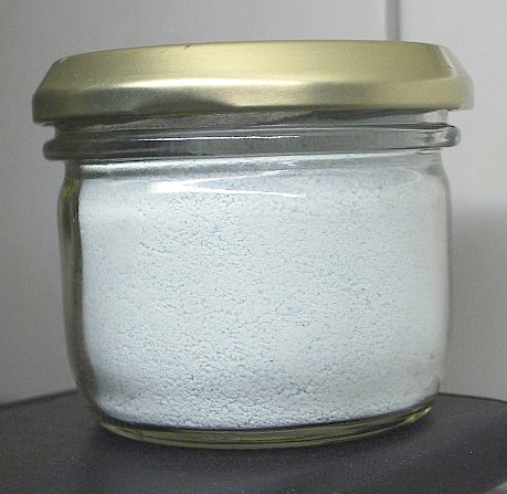 A glass jar filled with white powder, sealed with a metal lid.