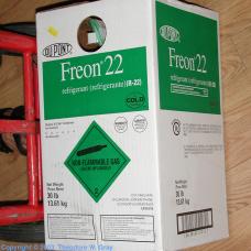A box of refrigerant labeled "Freon® 22," featuring a green diamond hazard symbol, placed on a wooden surface.